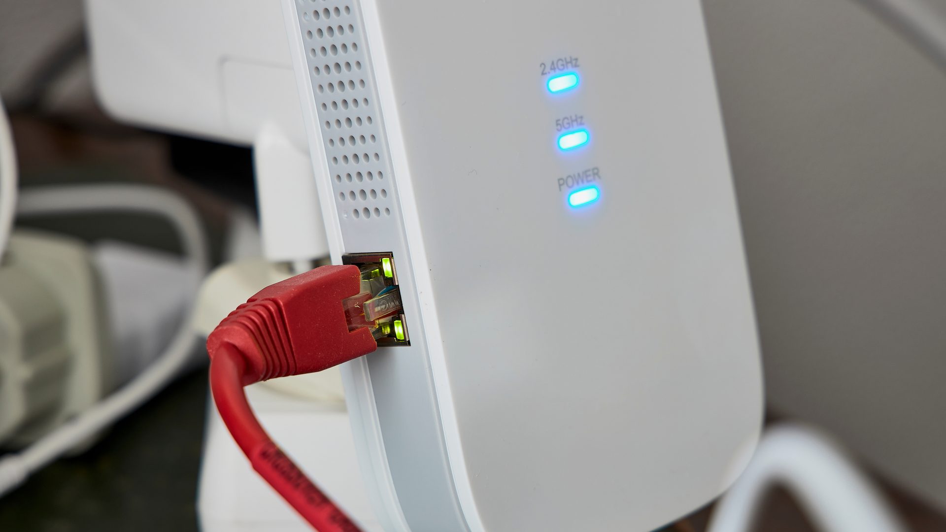 Repetidor Wi-Fi branco conectado à um cabo de rede vermelho