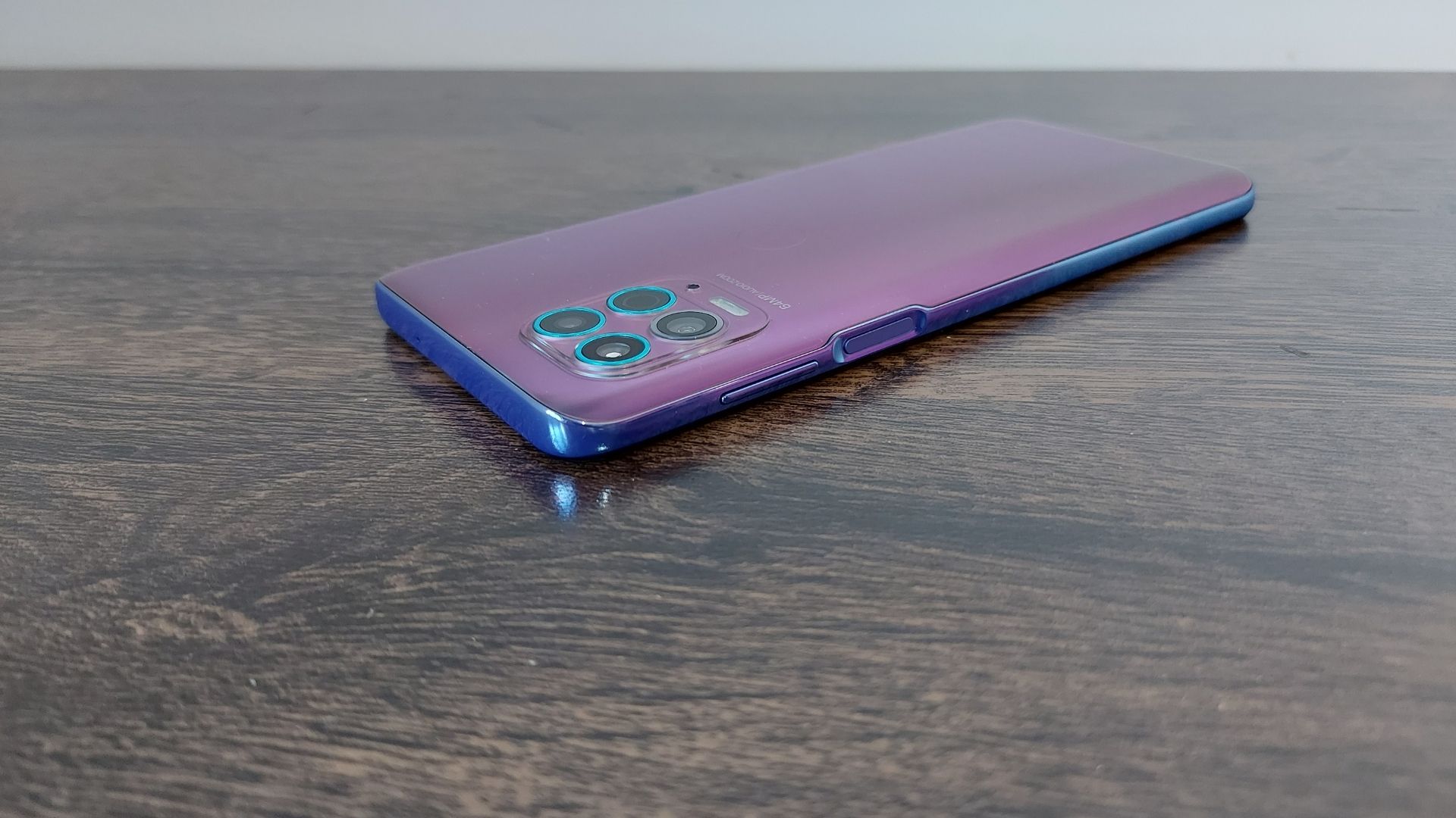 Moto G100 em cima de uma mesa de madeira e com parte traseira virada para cima