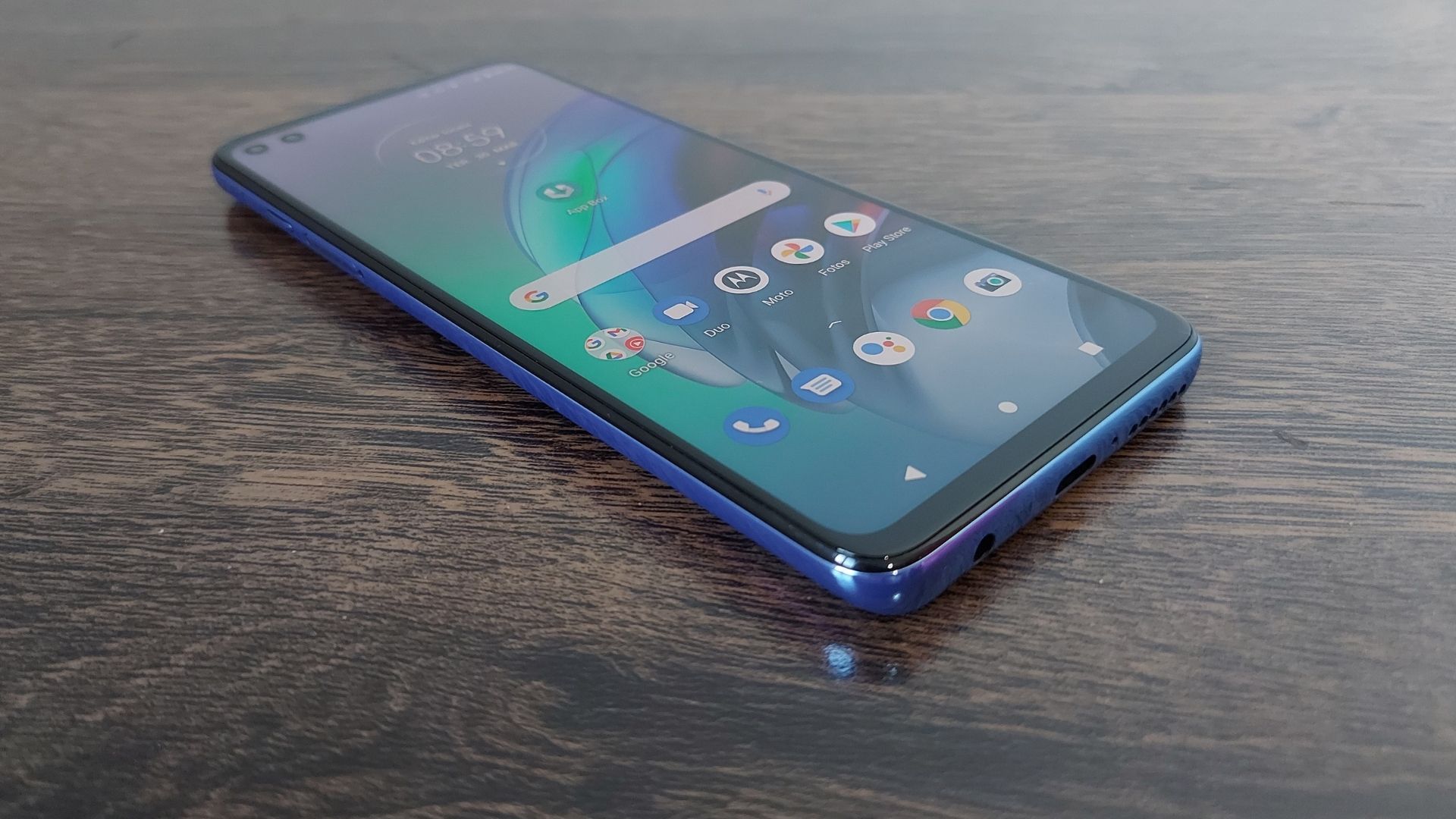 Moto G100 em cima de uma mesa de madeira e com parte frontal virada para cima