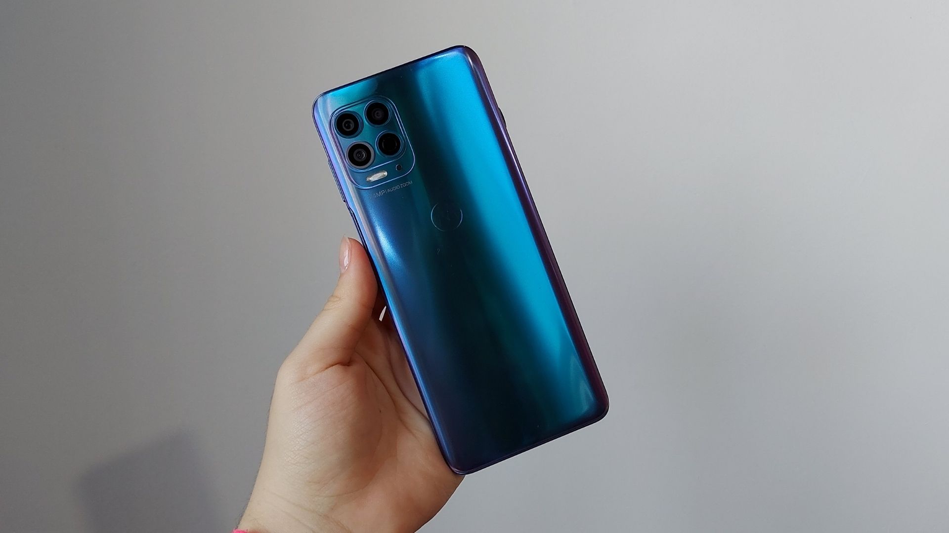 Mão segurando Moto G100 e exibindo parte traseira do celular