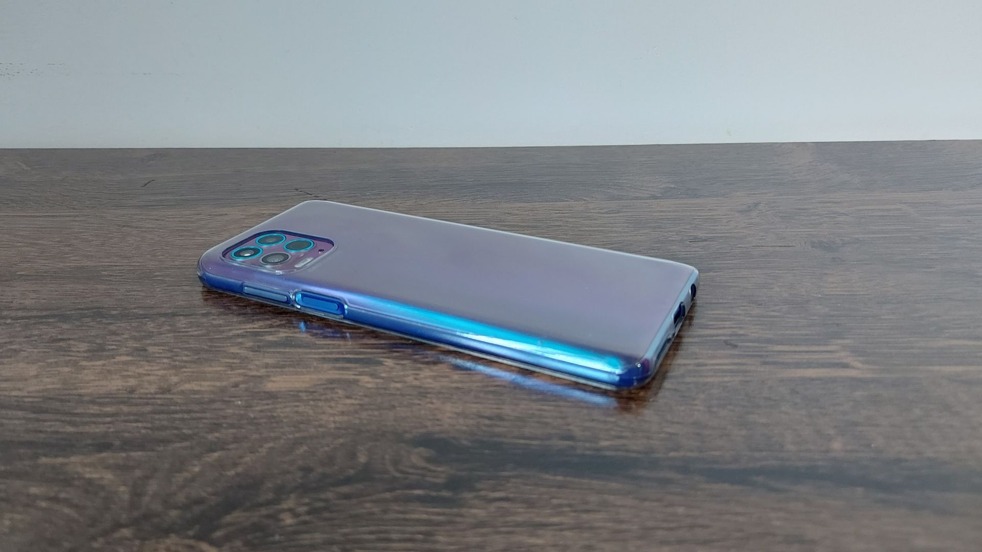 Moto G100 em cima de uma mesa de madeira e com parte traseira virada para cima e ângulo diferente