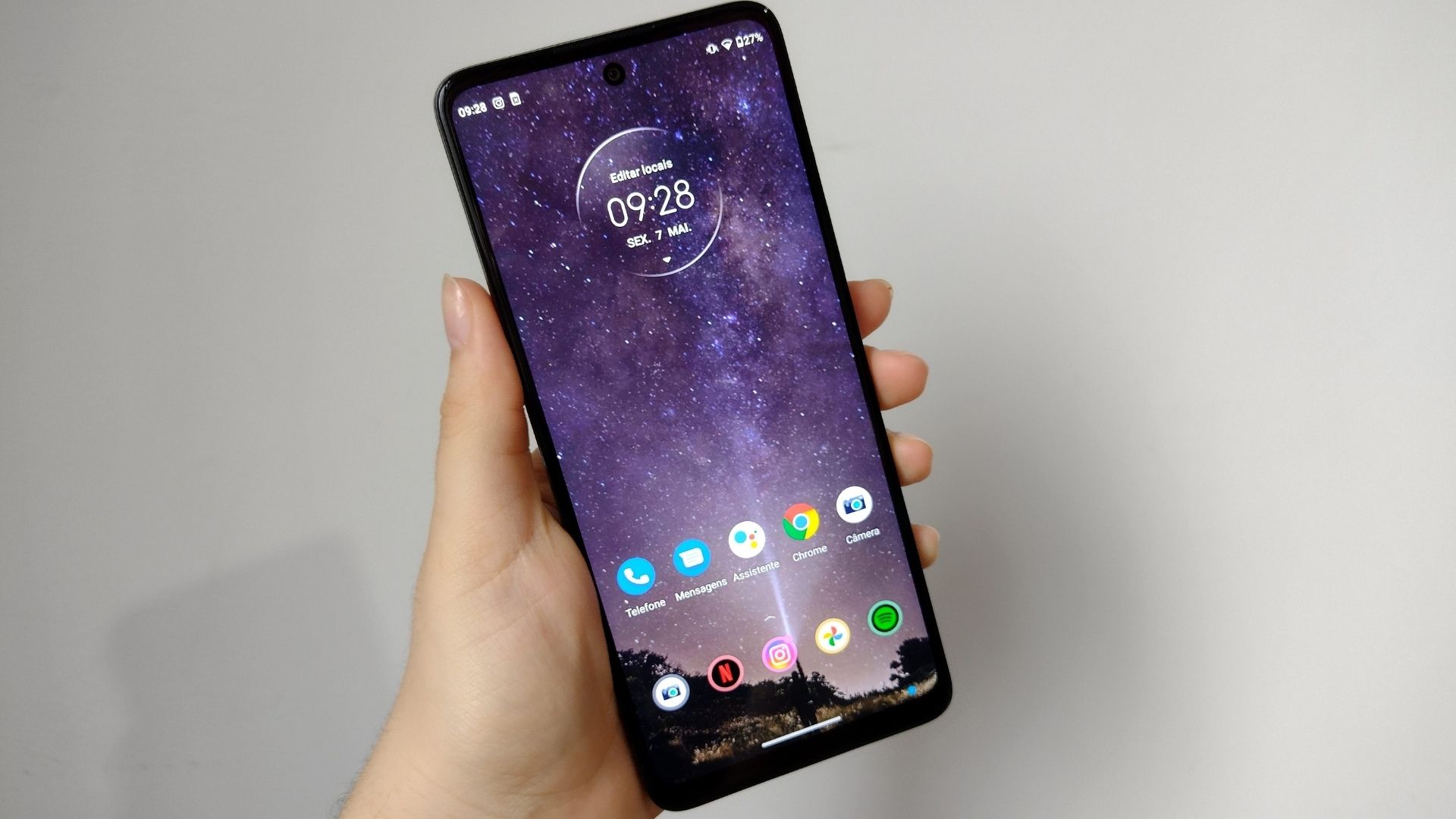 Imagem mostra mão segurando Moto G60 e exibindo parte frontal do celular